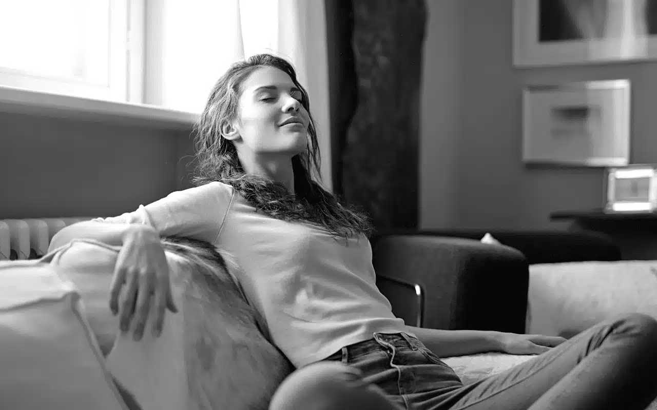 Woman sitting on couch relieved to read that inflation is cooling.